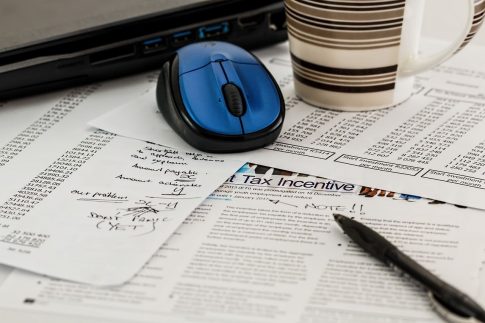 Piles of tax papers, a pen, and computer mouse.